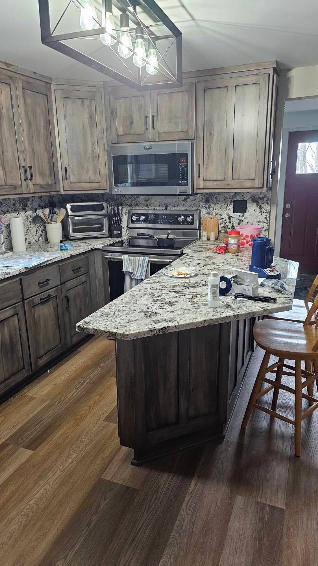 Kitchen with wood cabinets, granite countertops, and island. Stainless steel appliances.