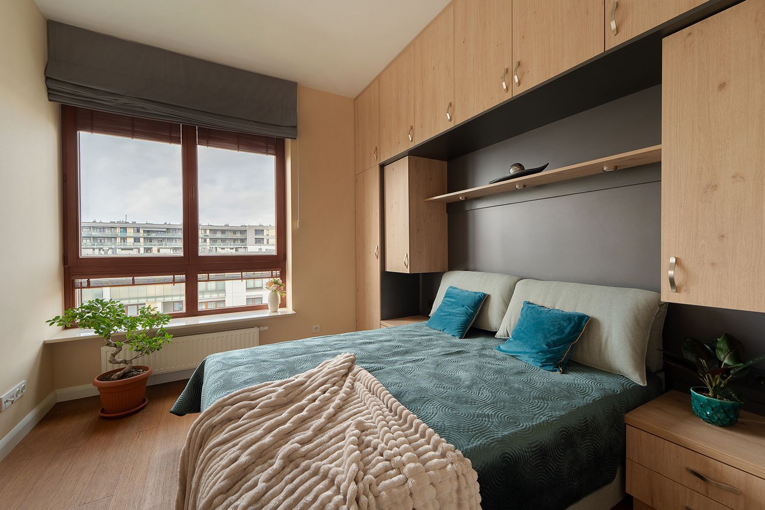 Bedroom with bed, built-in wooden cabinets, and a window with a city view.