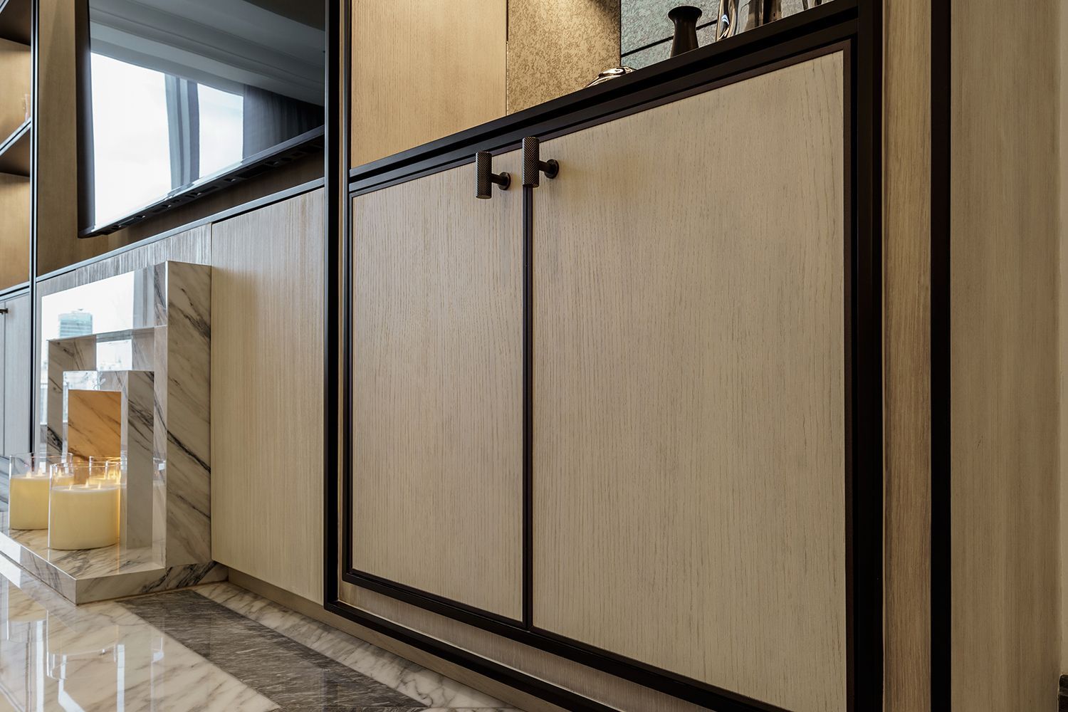 Wooden cabinet with black trim and handles, set in a modern interior with marble accents.