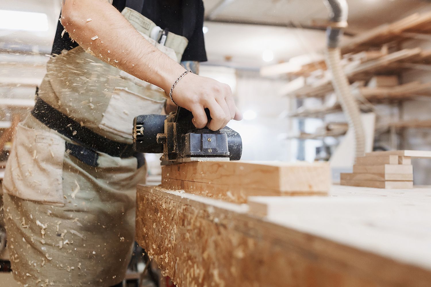 Carpenter using a planer on wood in a workshop, sawdust flying. Carpenter using a planer on wood in a workshop, sawdust flying.