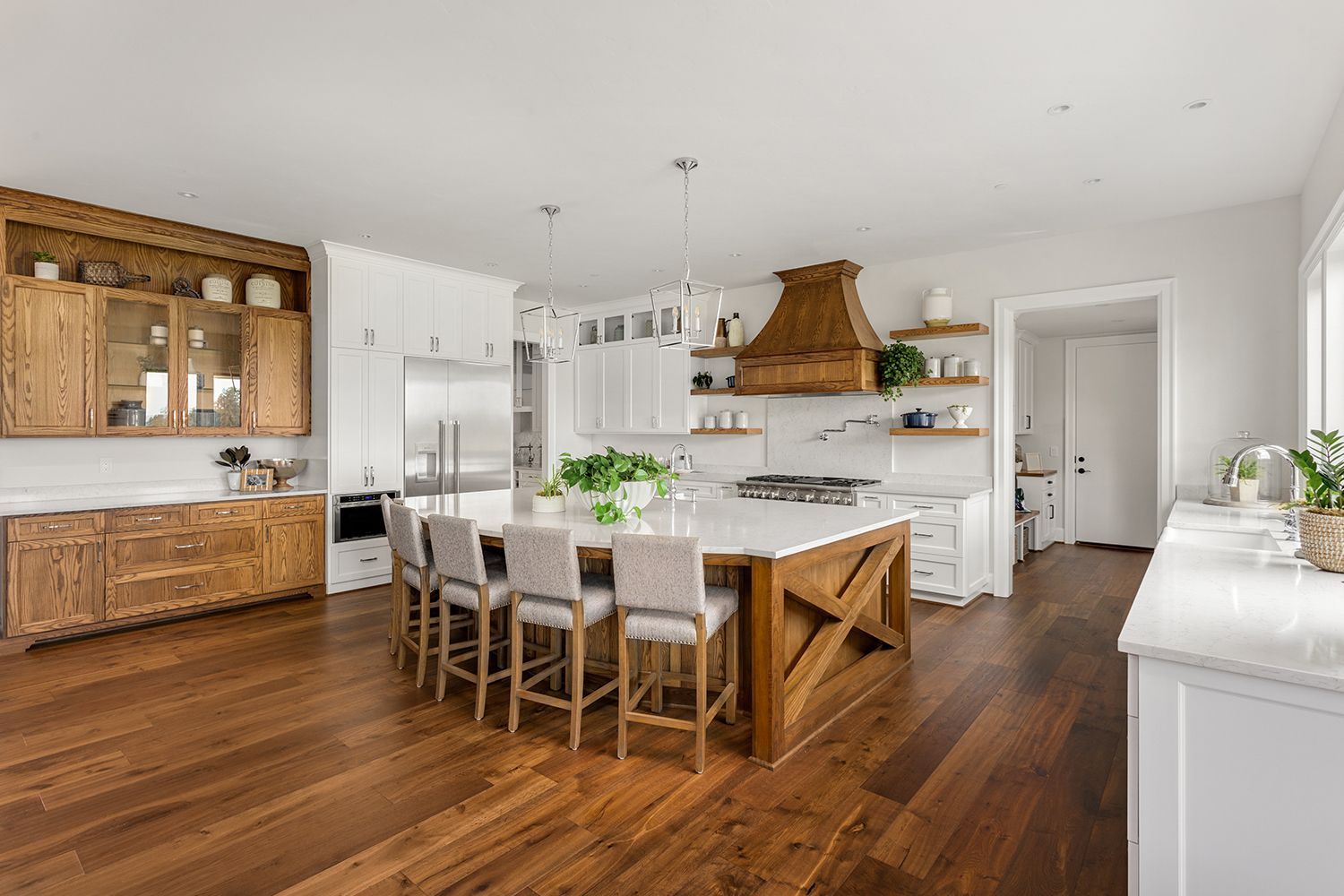 Spacious kitchen with wood floors and island. White cabinets, stainless steel appliances, and wooden accents. Spacious kitchen with wood floors and island. White cabinets, stainless steel appliances, and wooden accents.