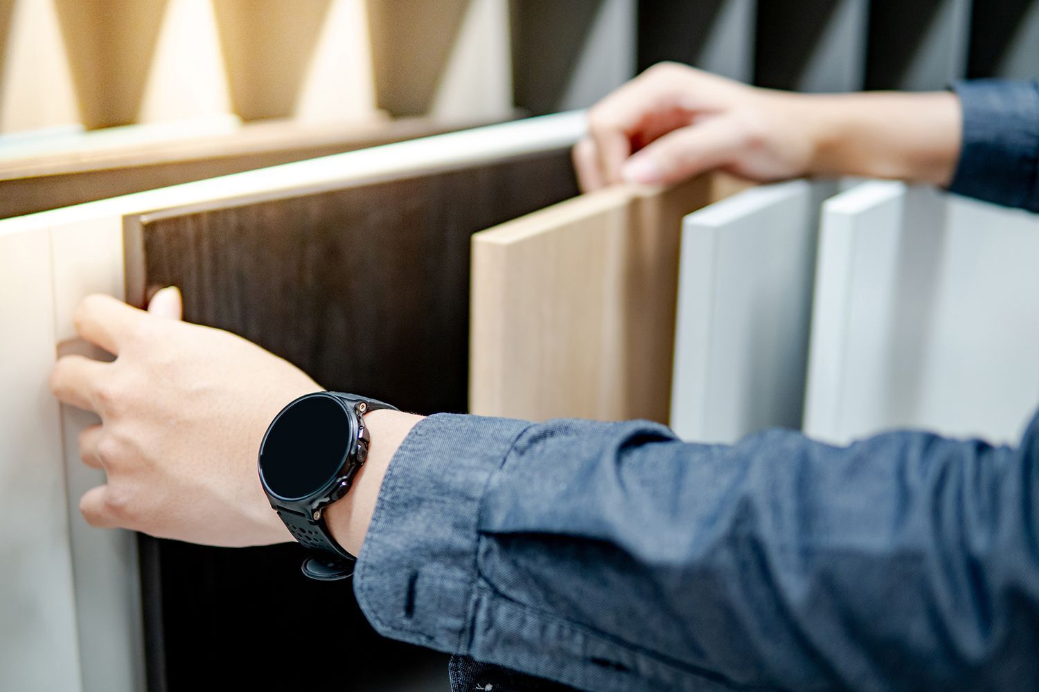 Person choosing wood samples from a display. Hands holding up various wood panels.