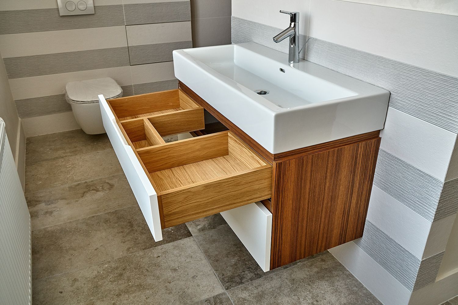 Bathroom vanity with open drawer; white sink and drawer front, wood cabinet, gray and white tile. Bathroom vanity with open drawer; white sink and drawer front, wood cabinet, gray and white tile.