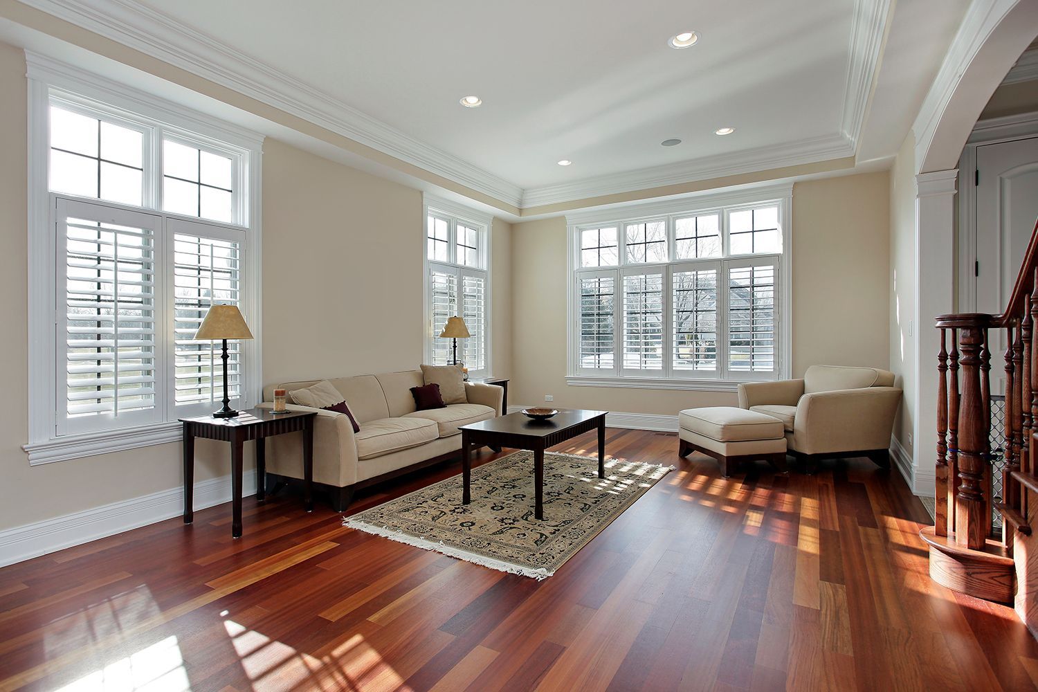 Living room with wood floor, beige walls, windows with shutters, sofa, chaise lounge, rug, coffee table. Living room with wood floor, beige walls, windows with shutters, sofa, chaise lounge, rug, coffee table.