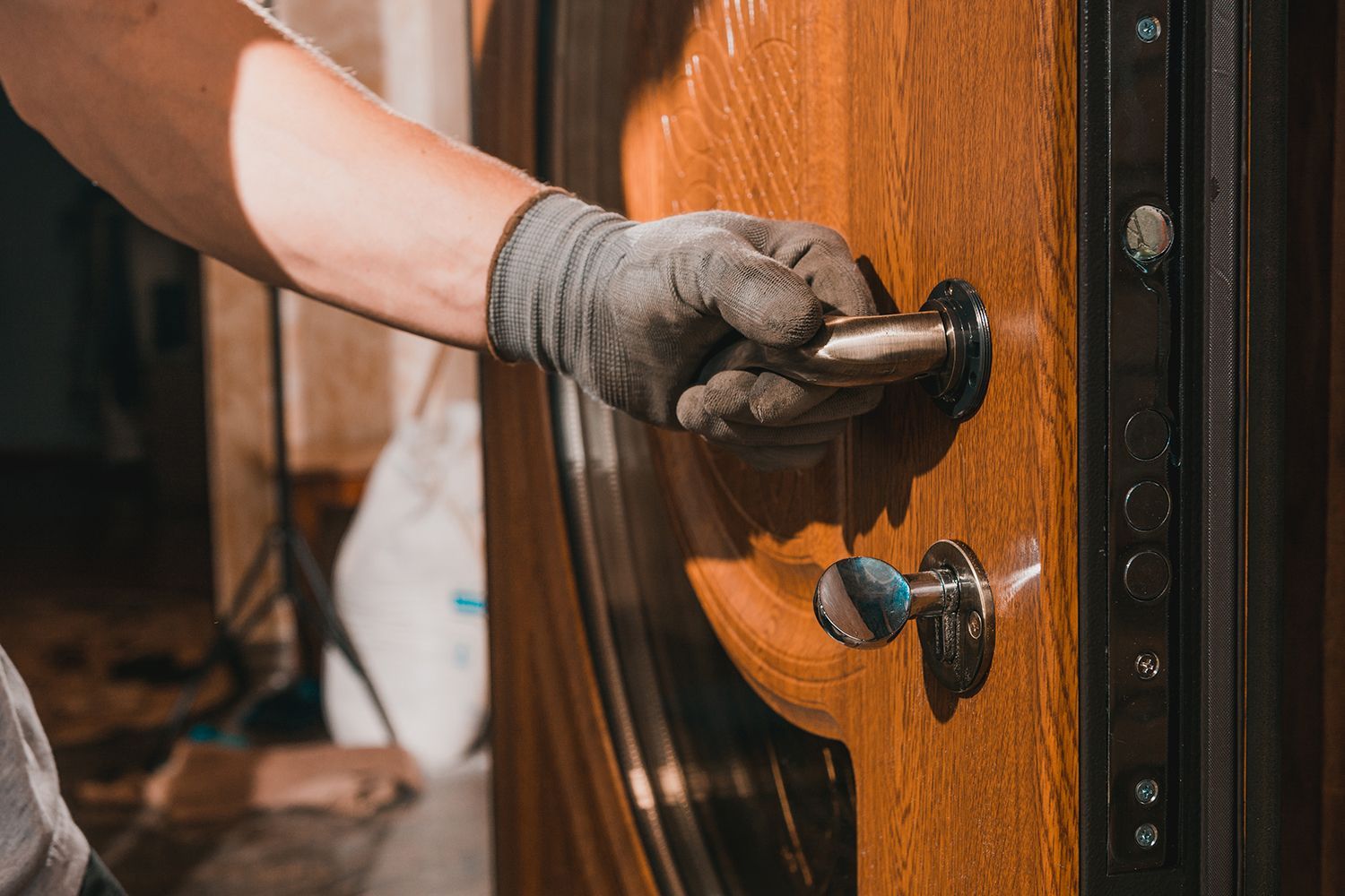 Hand in gray glove opening a wooden door with metal hardware. Hand in gray glove opening a wooden door with metal hardware.