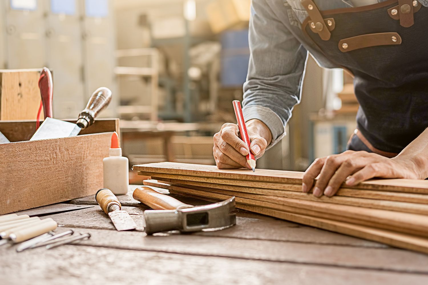 Carpenter marking wood planks with a pencil at a workbench in a workshop. Carpenter marking wood planks with a pencil at a workbench in a workshop.
