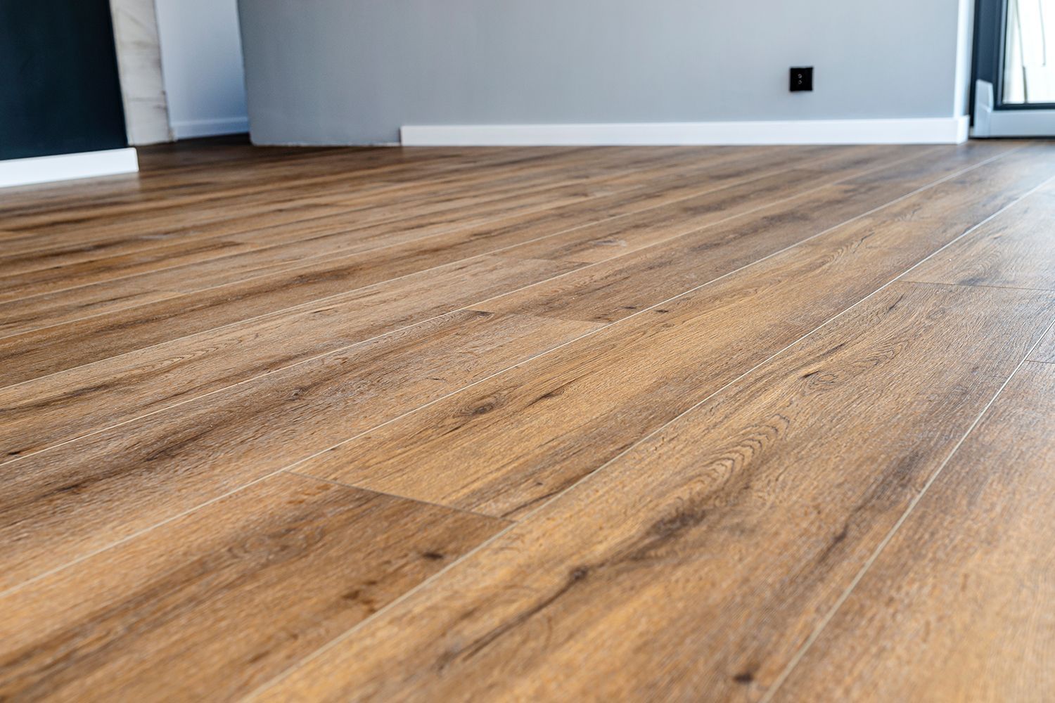 Close-up of wood-look flooring with gray and white walls in background. Close-up of wood-look flooring with gray and white walls in background.