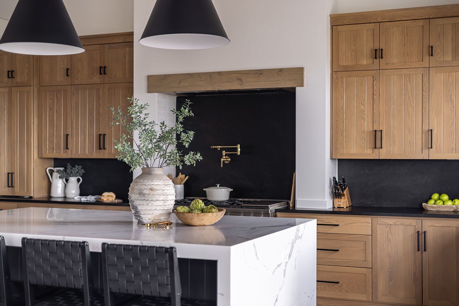 Modern kitchen with light wood cabinets, black accents, and a large island with seating.