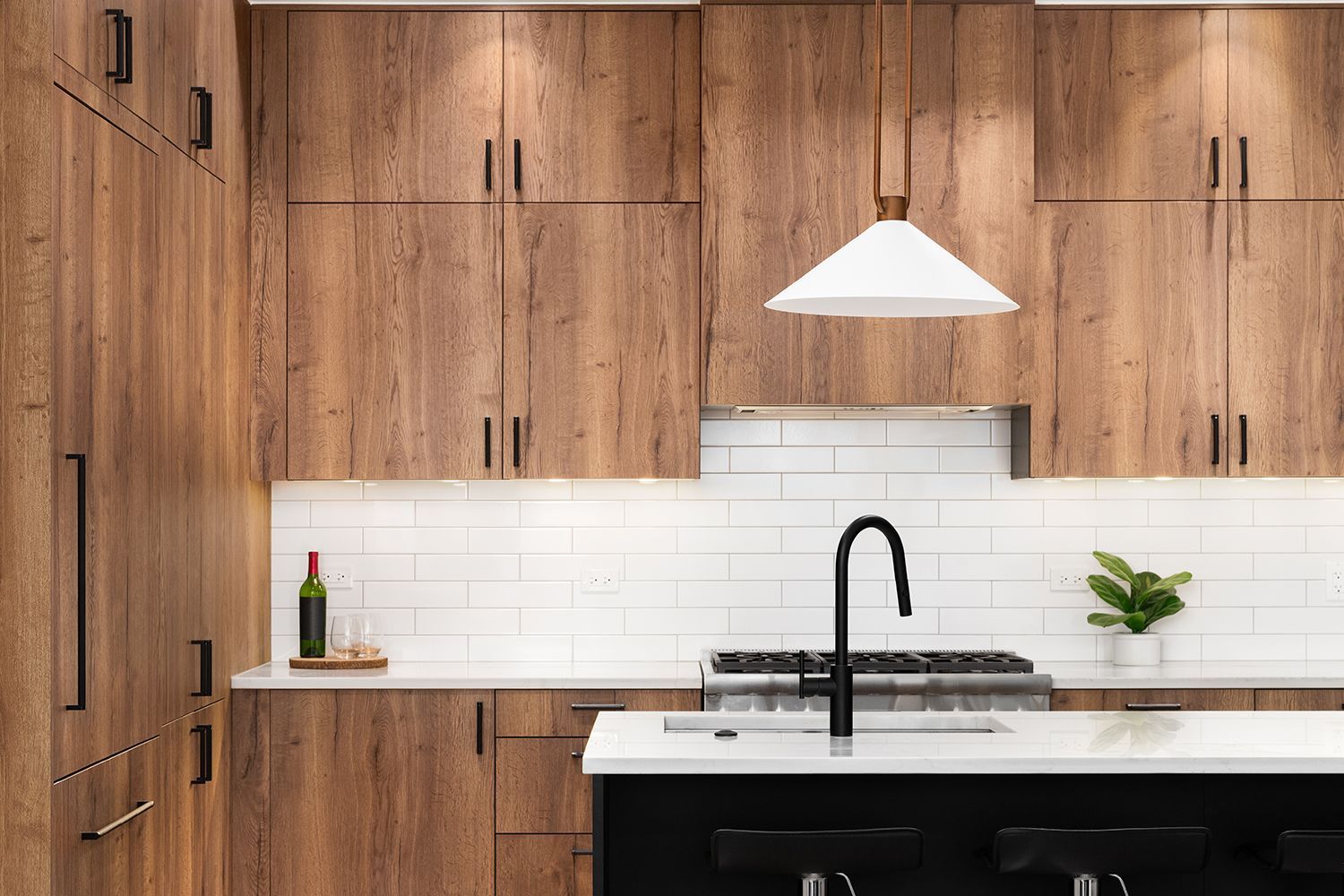 Kitchen with wood cabinets, white backsplash, black faucet, and pendant light.