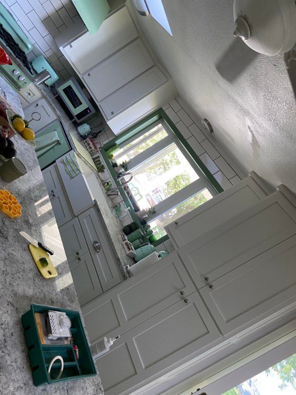 Kitchen with white cabinets, green trim and appliances.