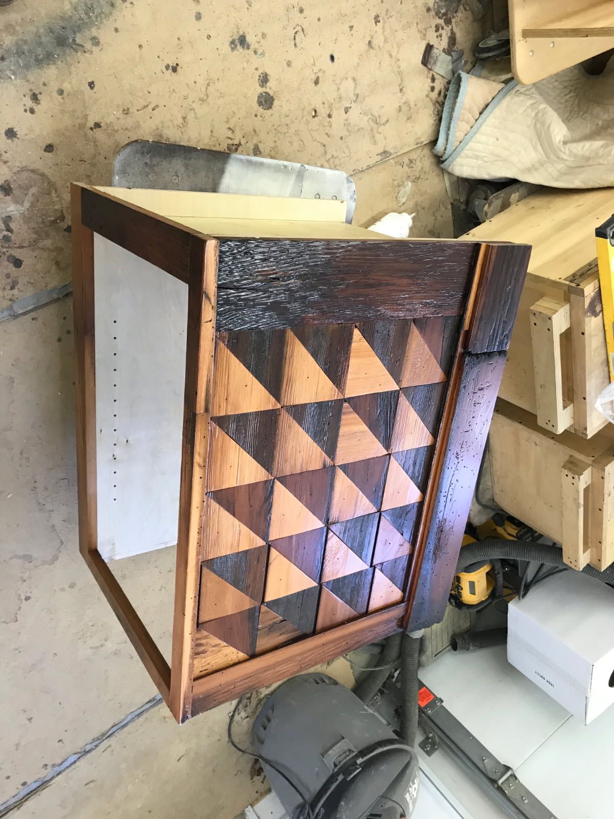 Wooden cabinet with geometric triangular design, outdoors.
