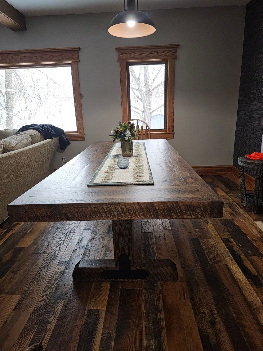 Rustic wooden dining table with a center base and a floral centerpiece. Rustic wooden dining table with a center base and a floral centerpiece.