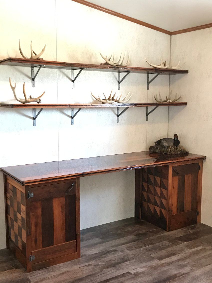 Rustic wooden desk with shelves holding antlers, against a light-colored wall.