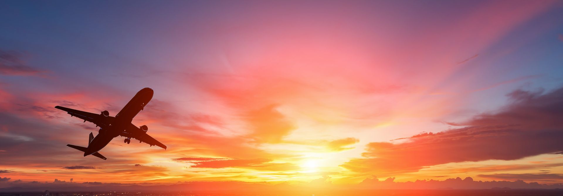 The silhouette of a passenger plane flying in sunset