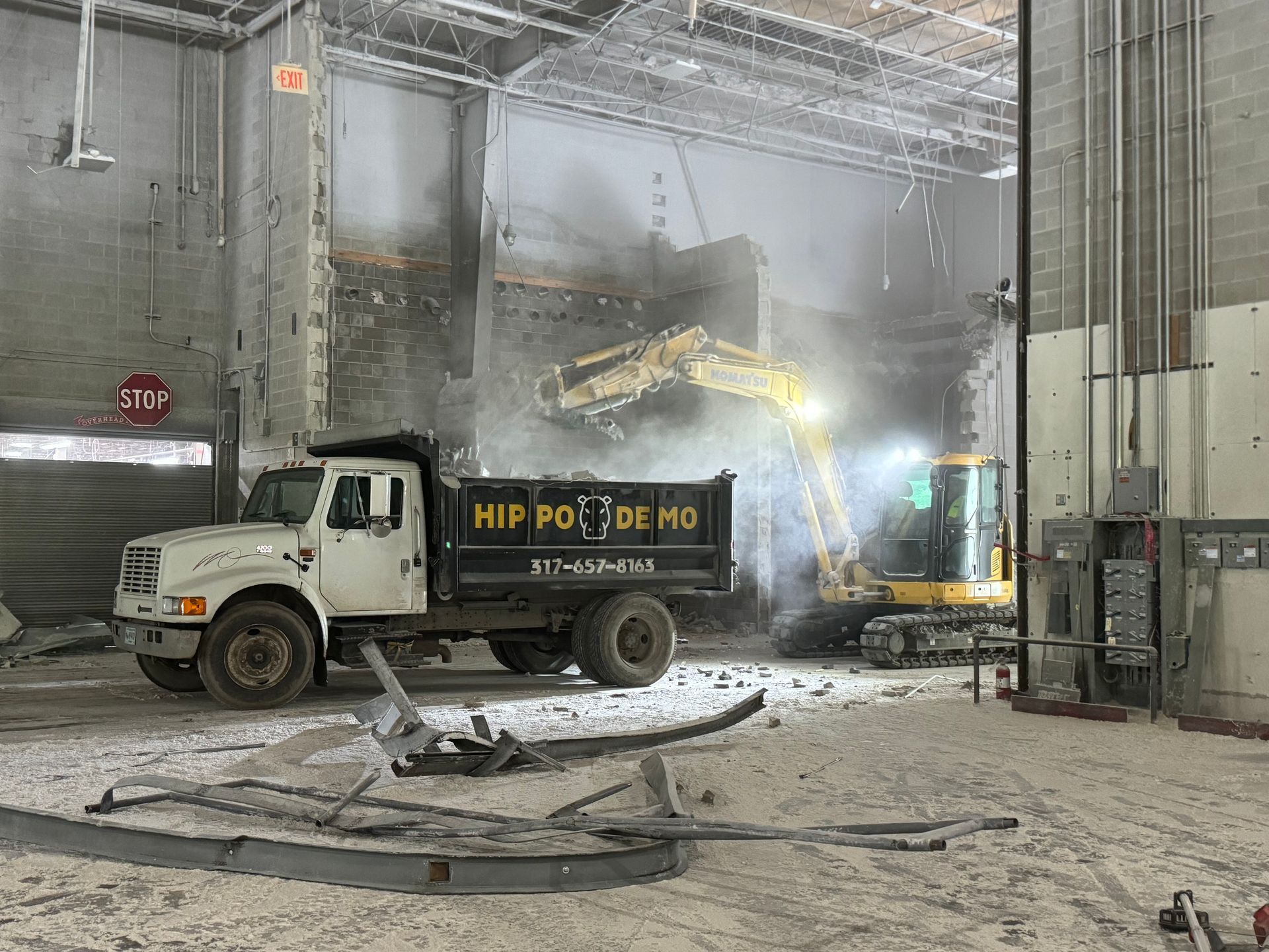 A dump truck is driving down a dirt road in a warehouse.