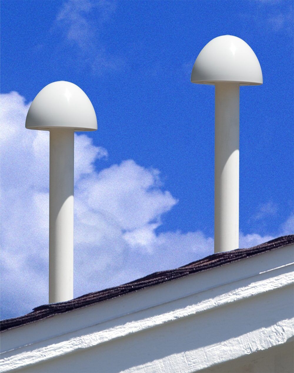 Two white vent on top of a building with a blue sky in the background