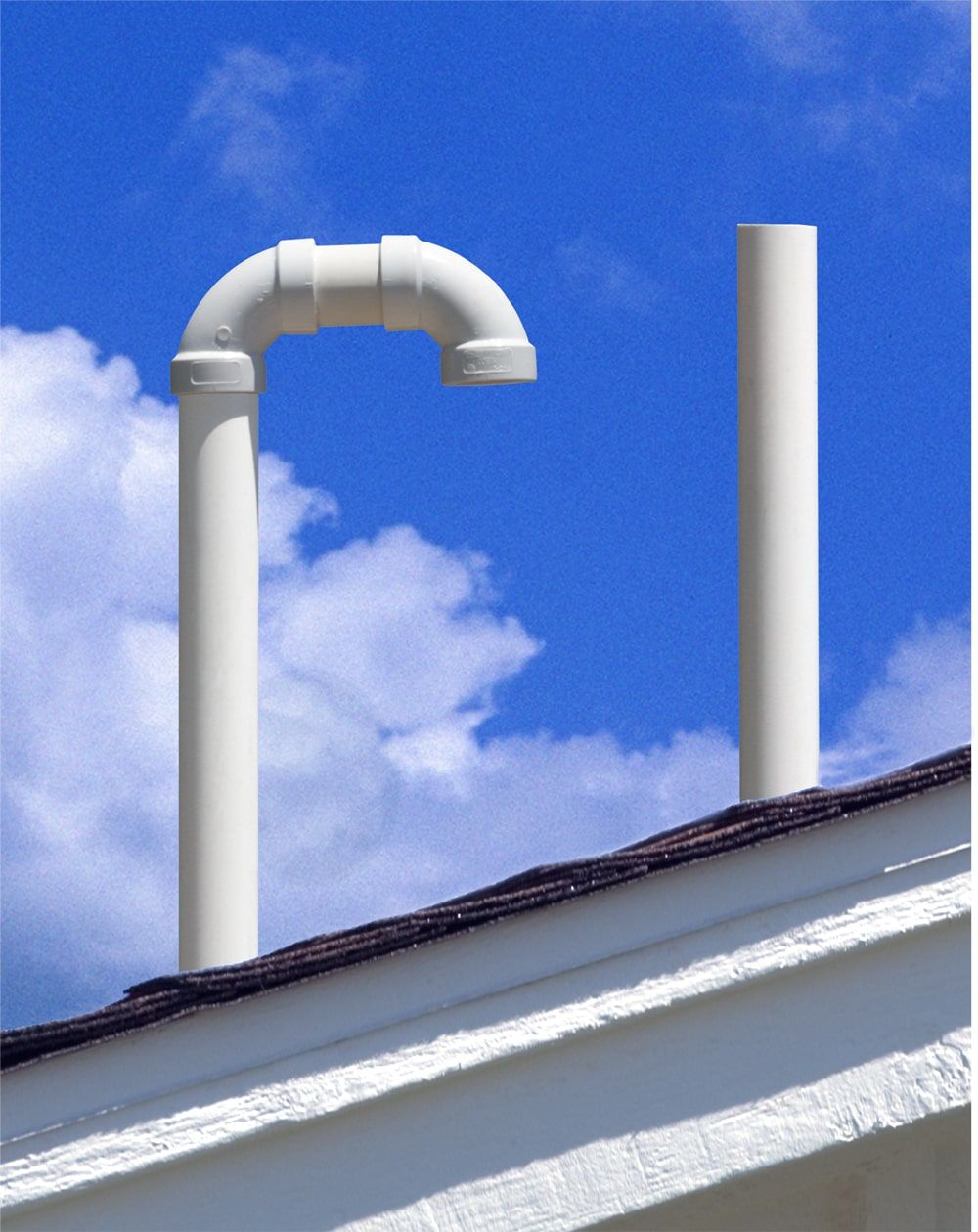 Two vent pipes on a roof with a blue sky in the background