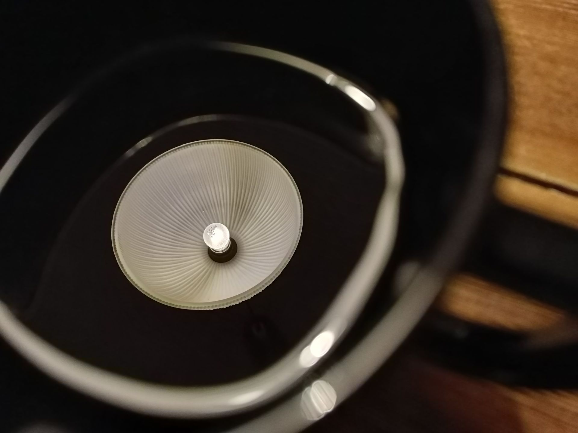 En bordslampa speglar sig i svart kaffe.