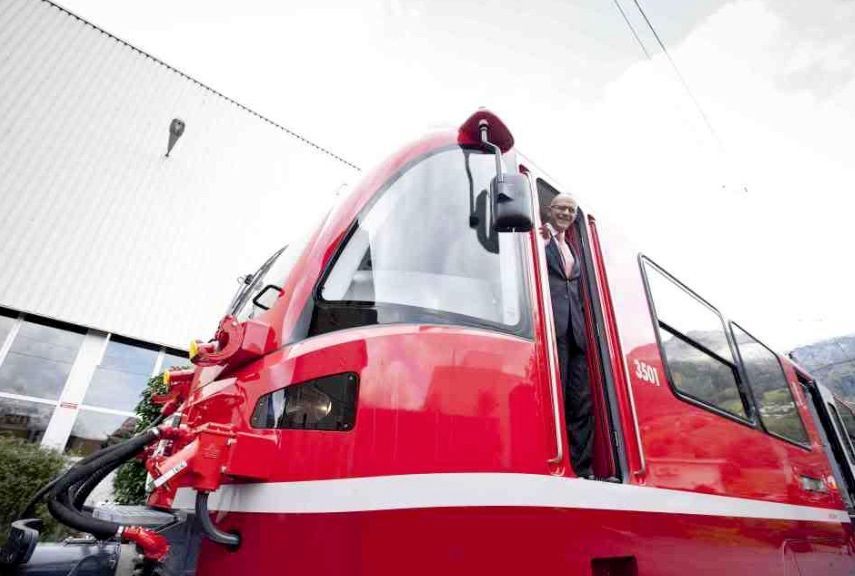 Vor einem Gebäude parkt ein rot-weißer Zug.