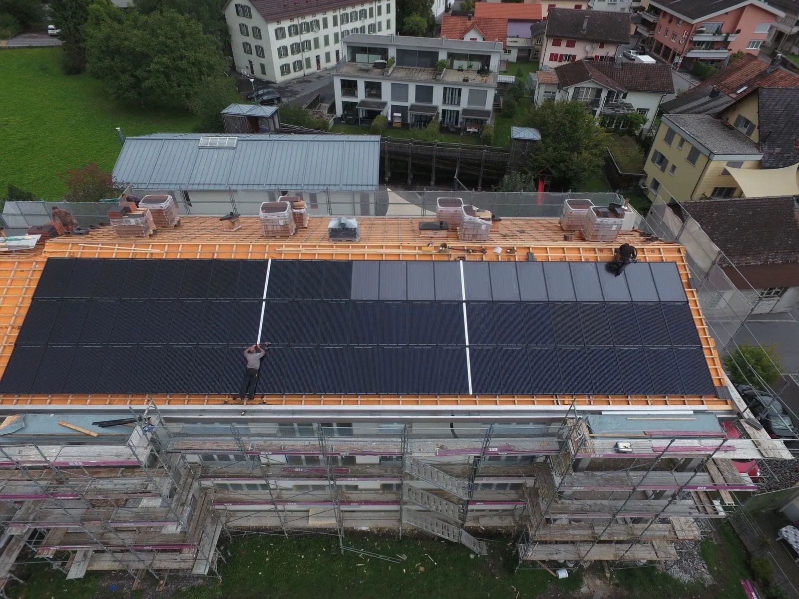 Eine Luftaufnahme eines im Bau befindlichen Gebäudes mit Solarmodulen auf dem Dach