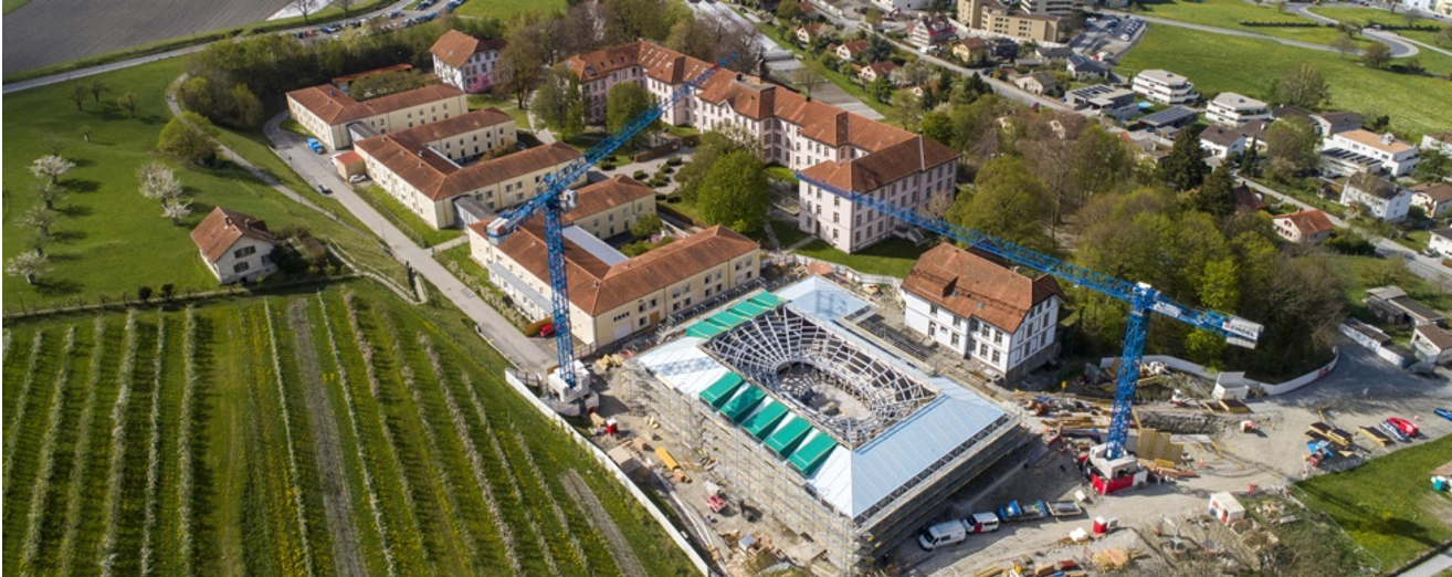 Eine Luftaufnahme eines im Bau befindlichen Gebäudes mit Kränen im Hintergrund.