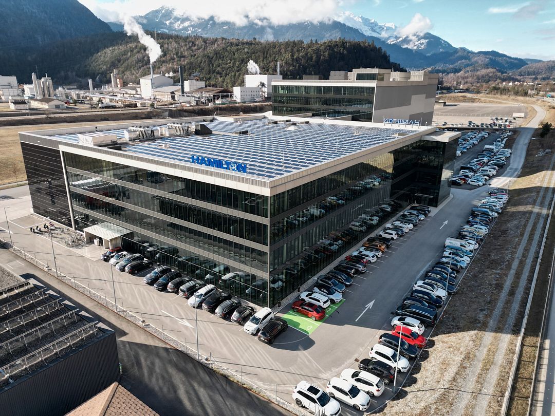 Eine Luftaufnahme eines großen Gebäudes, vor dem viele Autos geparkt sind.