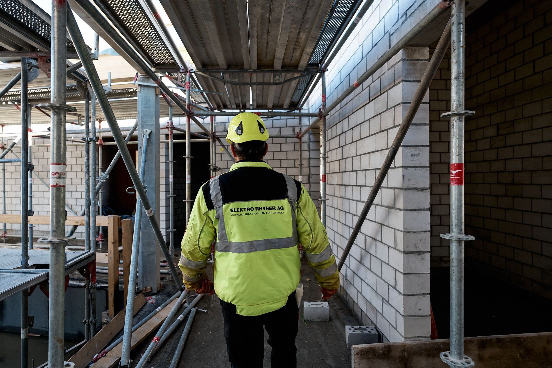 Ein Mann mit einem gelben Schutzhelm geht durch eine Baustelle