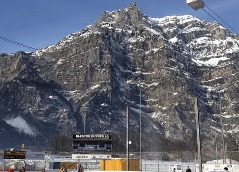 Ein großer schneebedeckter Berg liegt hinter einem Stadion