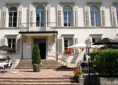 Ein Mann sitzt an einem Tisch vor einem weißen Gebäude