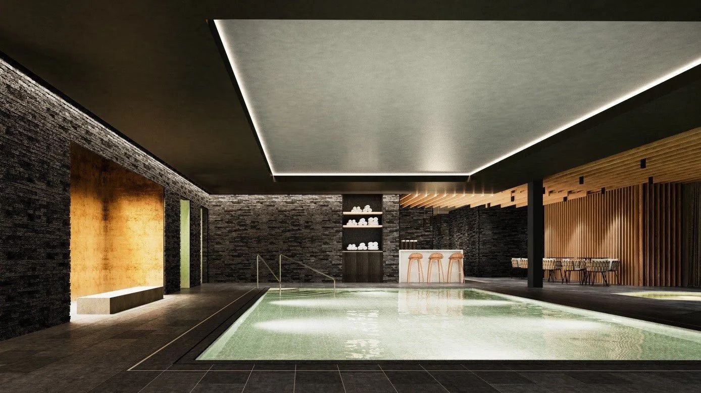 Indoor-Spa mit rechteckigem Pool, umgeben von dunklen Steinmauern und Holzakzenten. Leuchten erhellen den Raum.