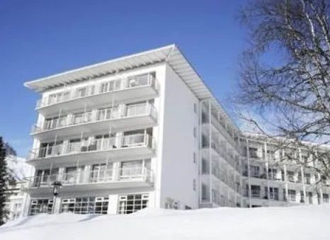 Ein großes weißes Gebäude mit vielen Fenstern ist schneebedeckt.