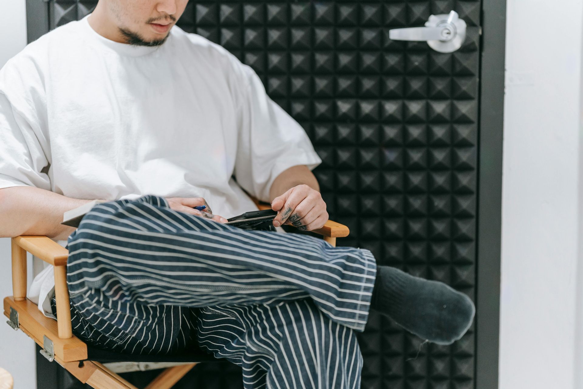 Un hombre está sentado en una silla de director con las piernas cruzadas.