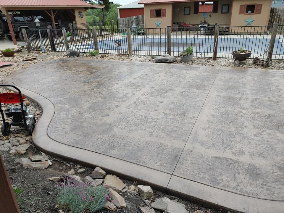 A concrete driveway in front of a house with a pool