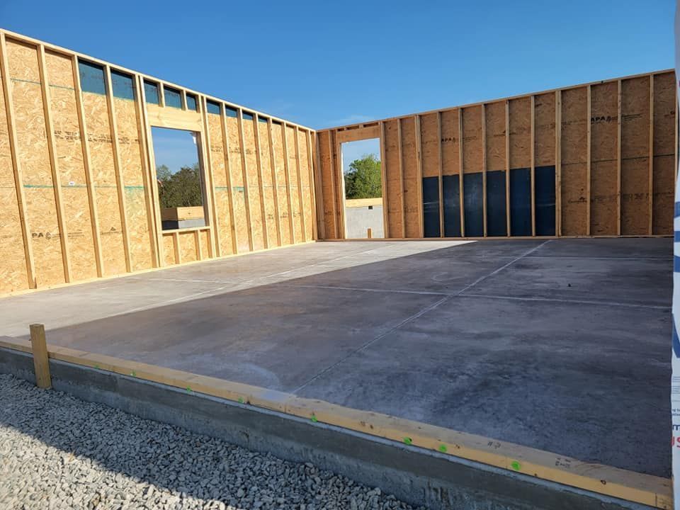 A building under construction with a concrete floor and wooden walls