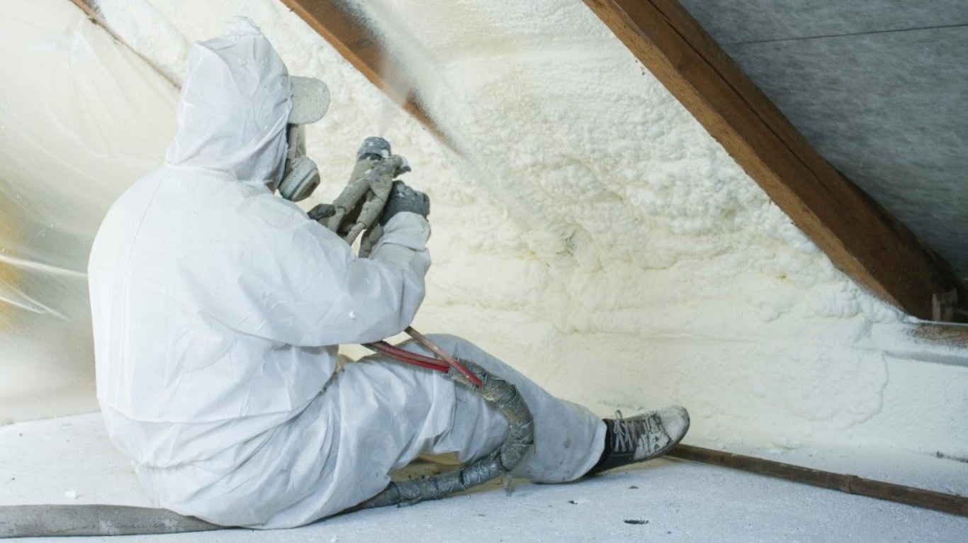 Installer applying spray foam attic insulation to roof deck in a residential attic in Buckeye, AZ.