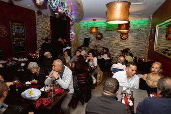 a group of people sitting at tables in the best Spanish restaurant in queens,  enjoying cocktails