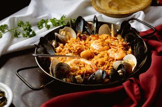 a pan filled with paella seafood and rice with a spoon in it