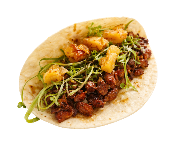 A taco on a white tortilla topped with dark, glazed meat, fresh herbs, and chunks of golden pineapple.