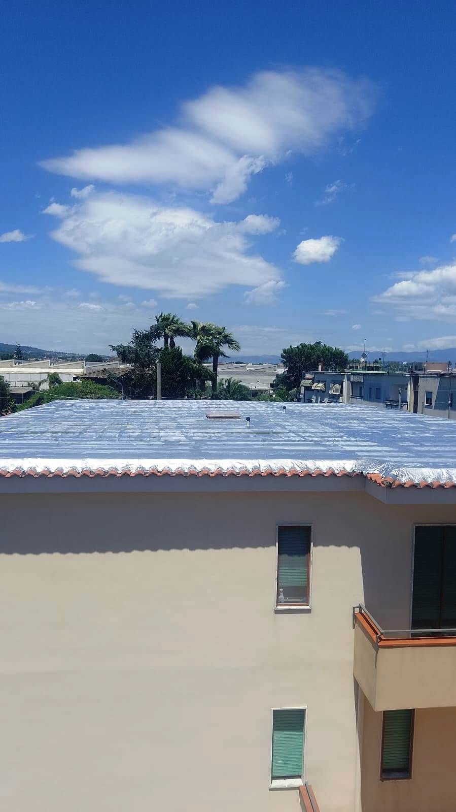 Un edificio con un balcone e un cielo azzurro con nuvole sullo sfondo.