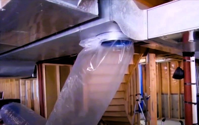 Basement ductwork during Aeroseal sealing process with clear plastic sheeting over vent and wooden s