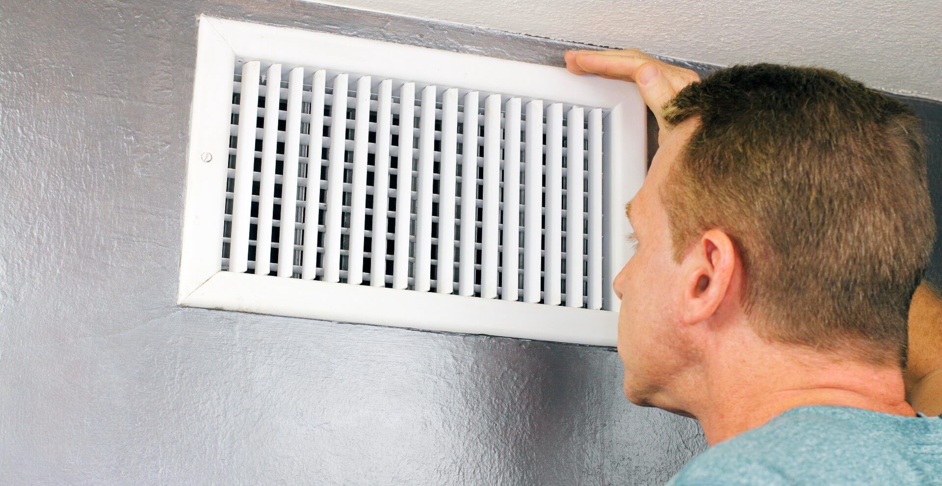 Man peering through his air vent that is on the wall