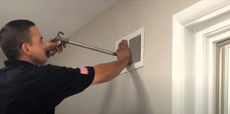 Expert cleaning air duct using specialized tools inside home