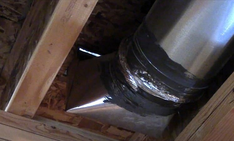 Ductwork joint with welding marks in wooden ceiling frame