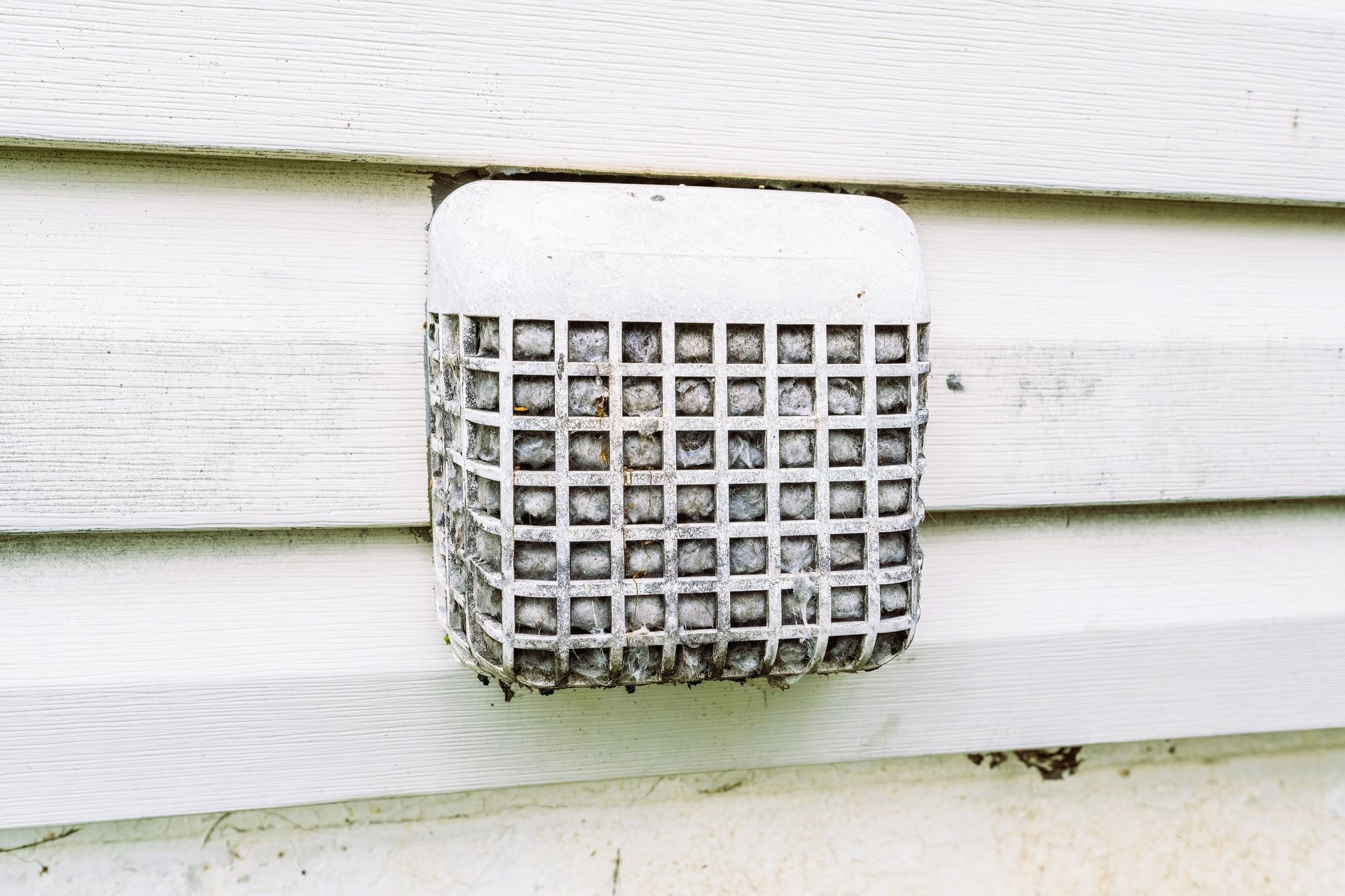 Clogged dryer vent guard with debris and lint, a safety hazard