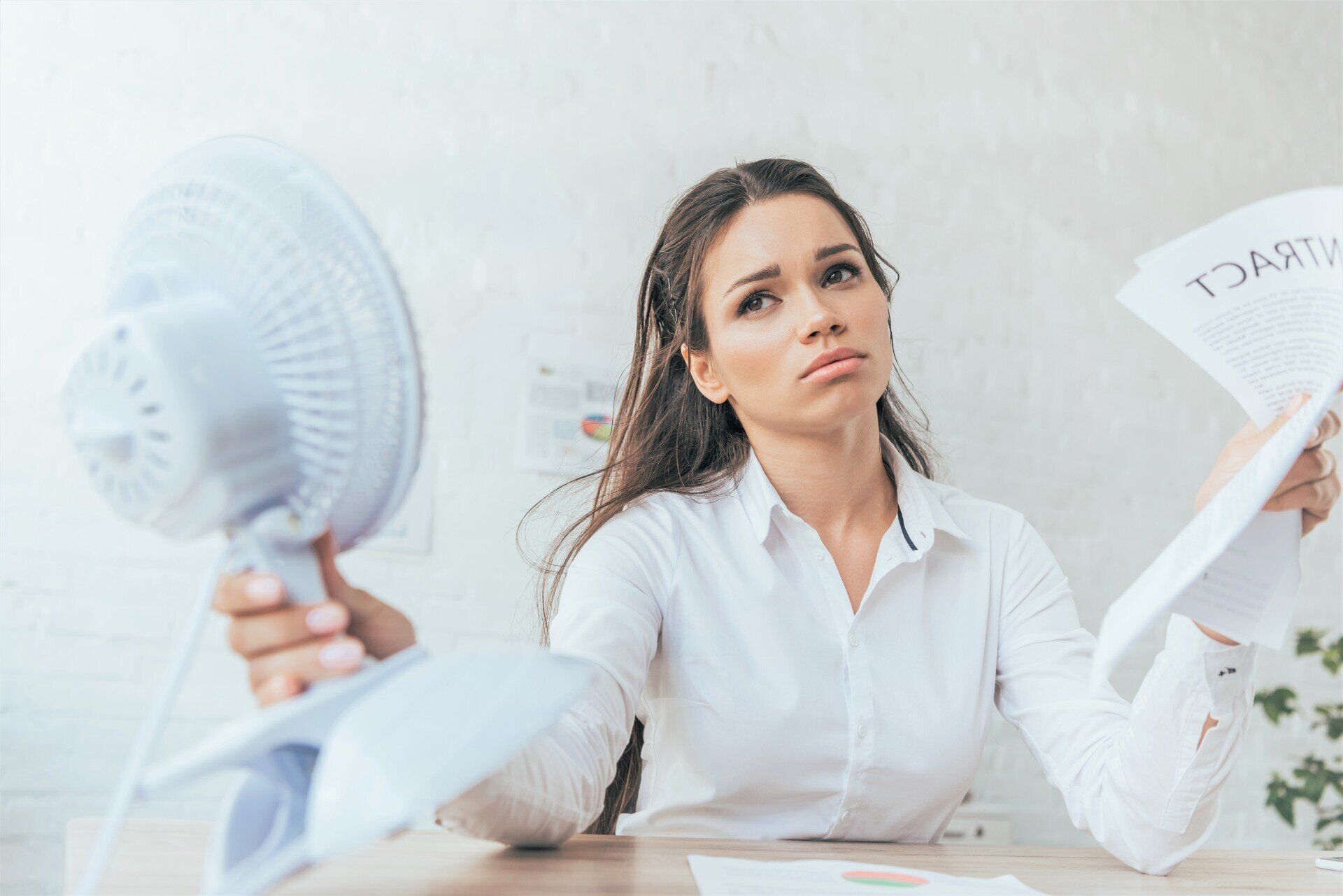 woman cooling off with electric fan because of summer heat