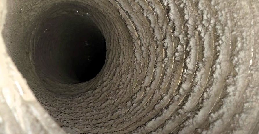 close-up view of a dirty spiral-patterned air duct with dust and debris