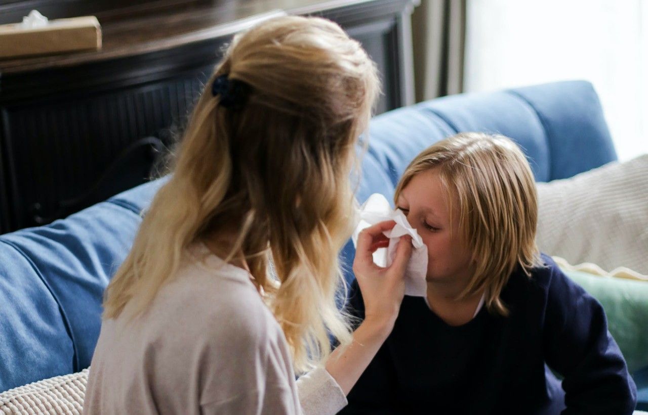 a mother helping her child who has a runny nose from allergies