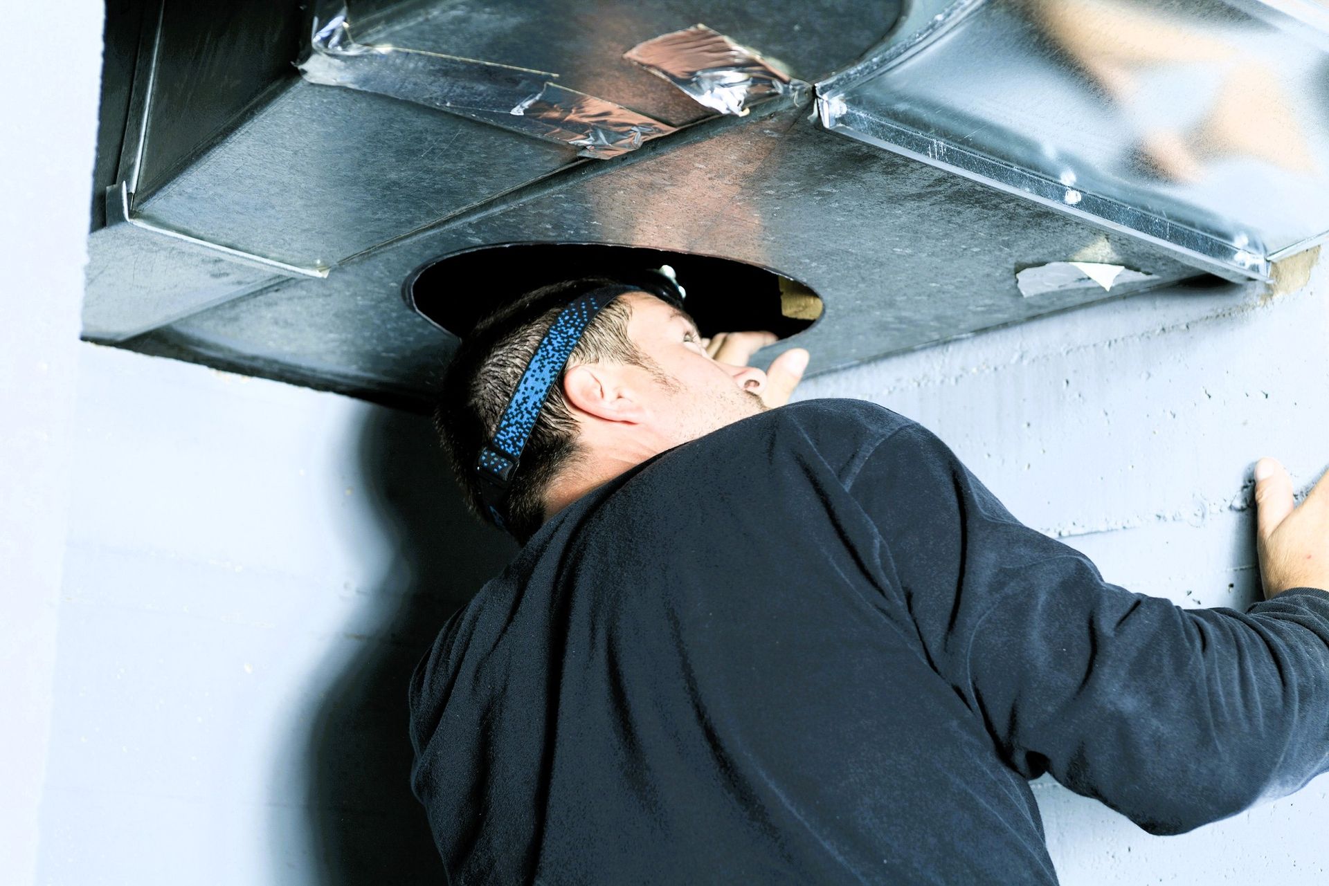 Person inspecting or repairing ductwork in a ceiling