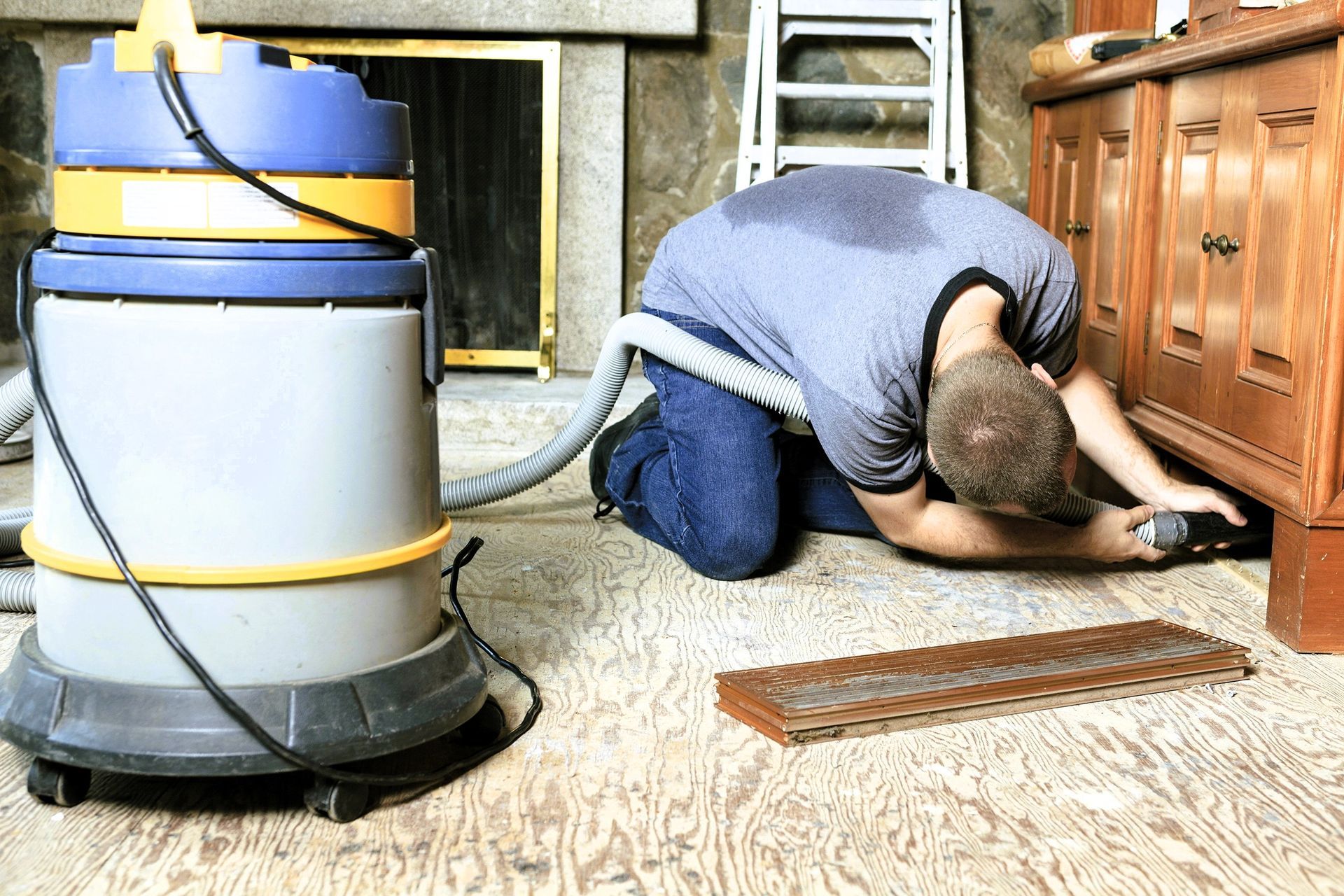 Person cleaning under a cabinet with a vacuum cleaner