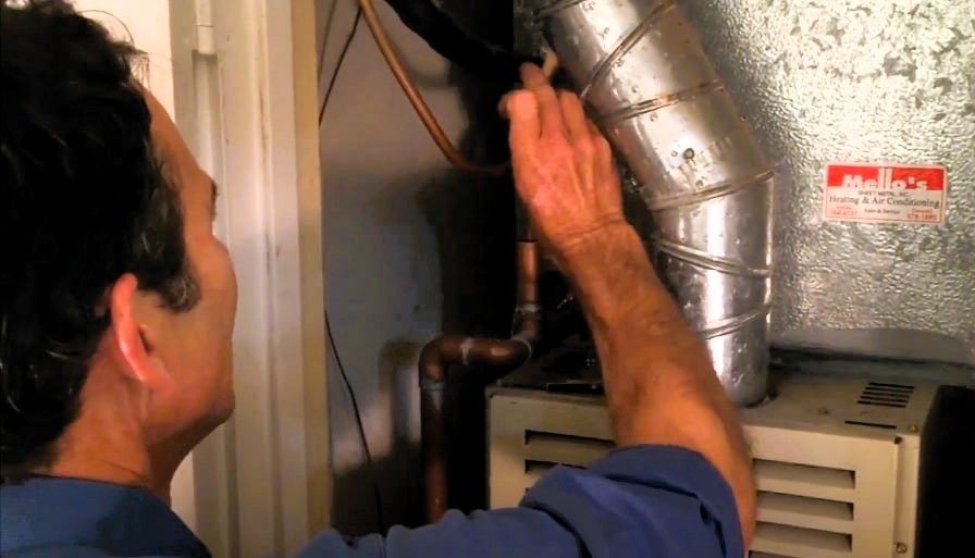 Man working on HVAC ductwork and sealing ducts in a utility area.